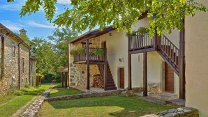 A stone building with a wooden staircase and a balcony with hanging plants. - Holiday home for nature lovers in a quiet location (Buzet)