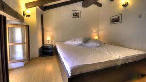 A bedroom with a wooden ceiling, a bed with white bedding, two wall-mounted lamps, and a small nightstand. - Holiday home for nature lovers in a quiet location (Buzet)