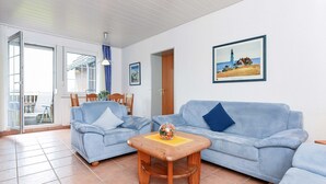 En stue med to lyseblå sofaer, et træsofabord og et maleri af et fyrtårn.