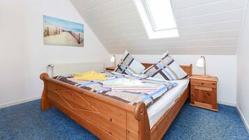 Ein Schlafzimmer mit Schräge, einem hölzernen Bett, einem Nachttisch und einem Bild an der Wand.