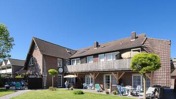 Ein zweistöckiges Gebäude mit Balkon, Sitzgelegenheiten im Freien und einem gepflegten Rasen.