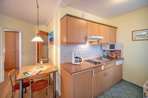 Una cocina compacta con armarios de madera, microondas integrado y cafetera sobre la encimera.