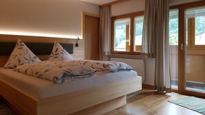 Un dormitorio con cama, cabecero de madera, una ventana con cortinas y vistas al exterior.
