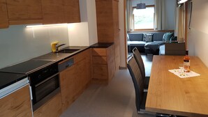 Una cocina moderna con armarios de madera, una encimera negra y un comedor con mesa y sillas de madera.