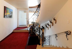 A staircase with ornate metal railings, a red carpeted floor, and a door leading to another room. - Apartment 2 - Rüf Marlene (Au)