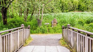 Ein Holzweg, der zu einem Friedhof führt, mit Grabsteinen, auf denen 'Elvastnet' und 'Kyrkjestien' stehen.