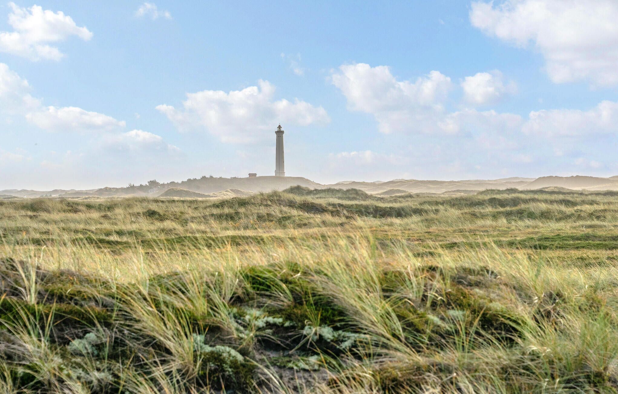 Un faro su una collina erbosa, con cielo sereno.