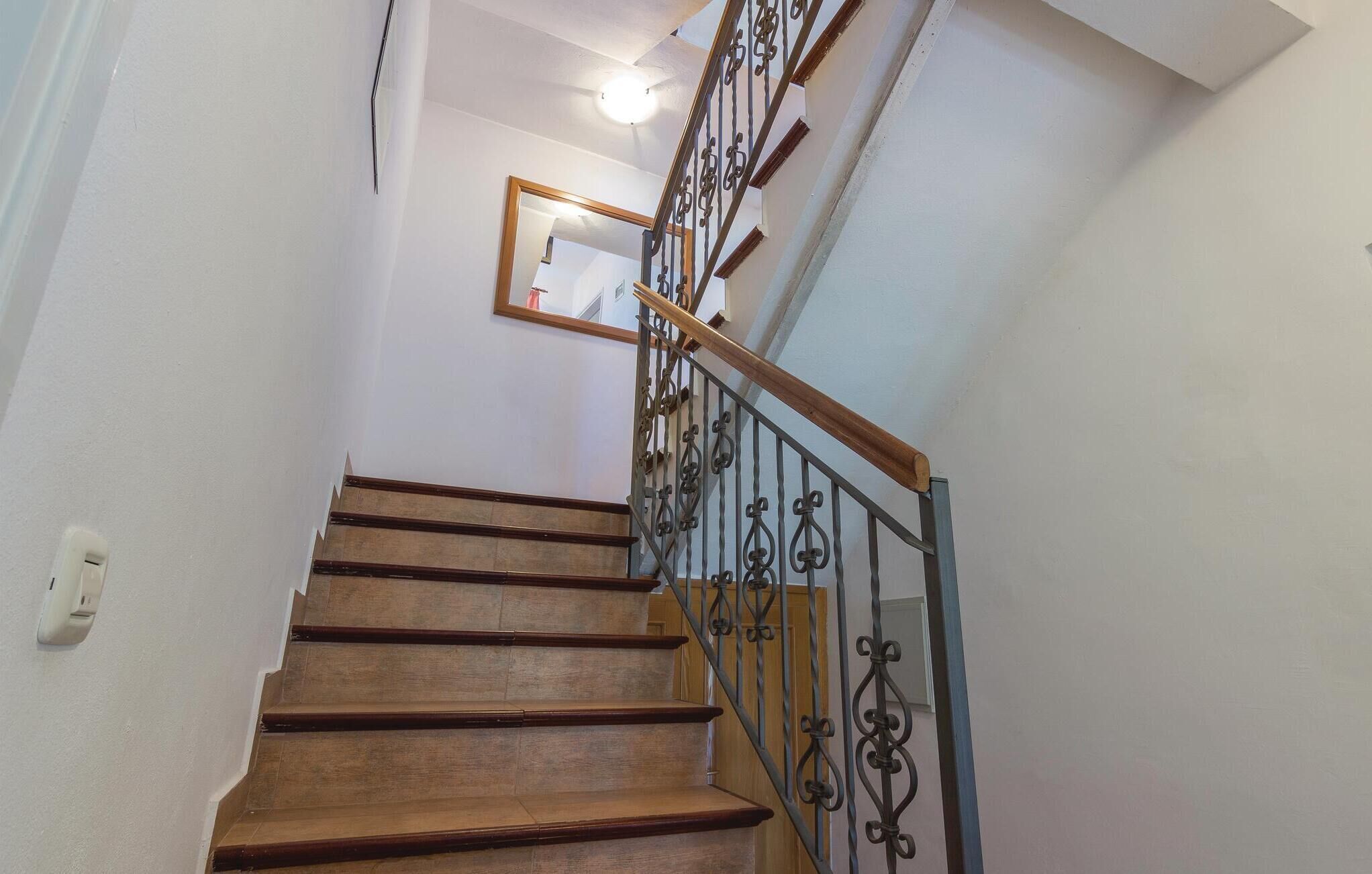 A wooden staircase with a metal railing and a mirror on the wall.