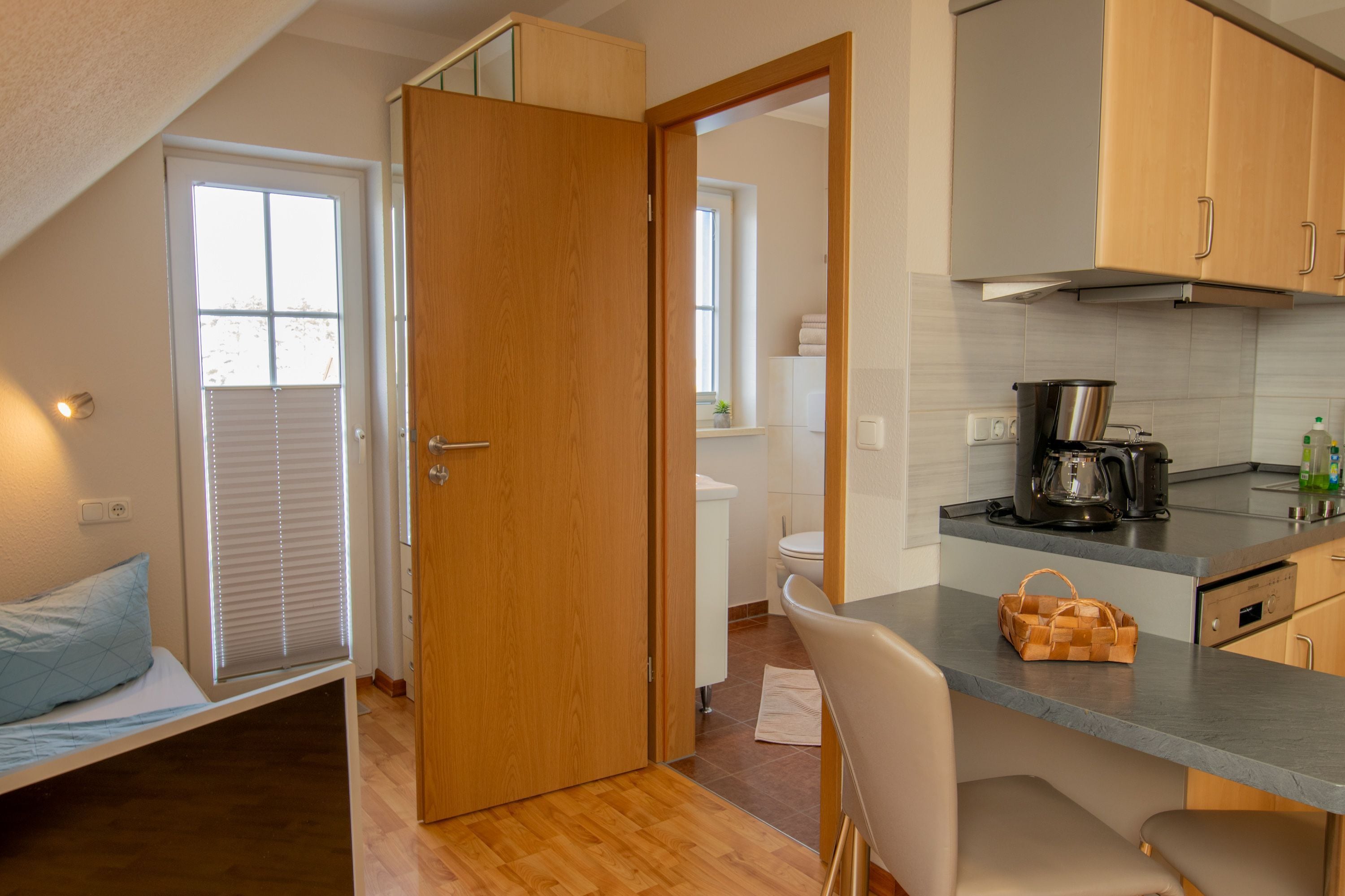 A compact kitchen with a dining area, a visible window, and a door leading to a bathroom.