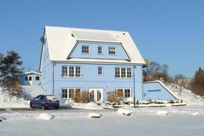 A two-story house with a snow-covered roof and a garage.