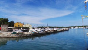 Un port de plaisance avec des bateaux amarrés, une grue et des bâtiments en arrière-plan.