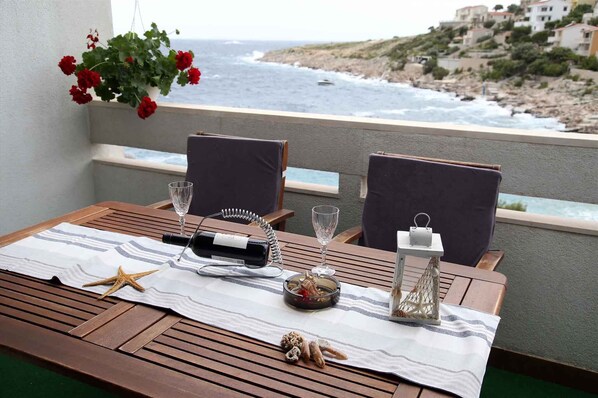 A balcony table with two chairs, a starfish, a bottle, a glass, and a candle holder.