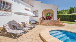 A pool area with lounge chairs, a small patio with a table and chairs, and a clear blue swimming pool. - Stunning home in Jávea (Jávea)