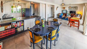 Una cocina moderna con comedor, que incluye una isla central, sillas y una estantería.