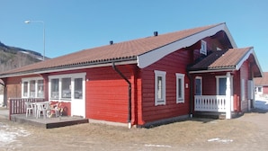 A red building with a white porch and a covered outdoor seating area.