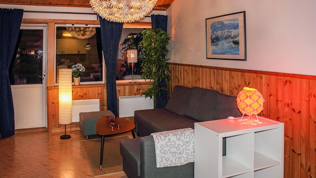 A cozy living room with a sofa, a small table, a lamp, and a plant.