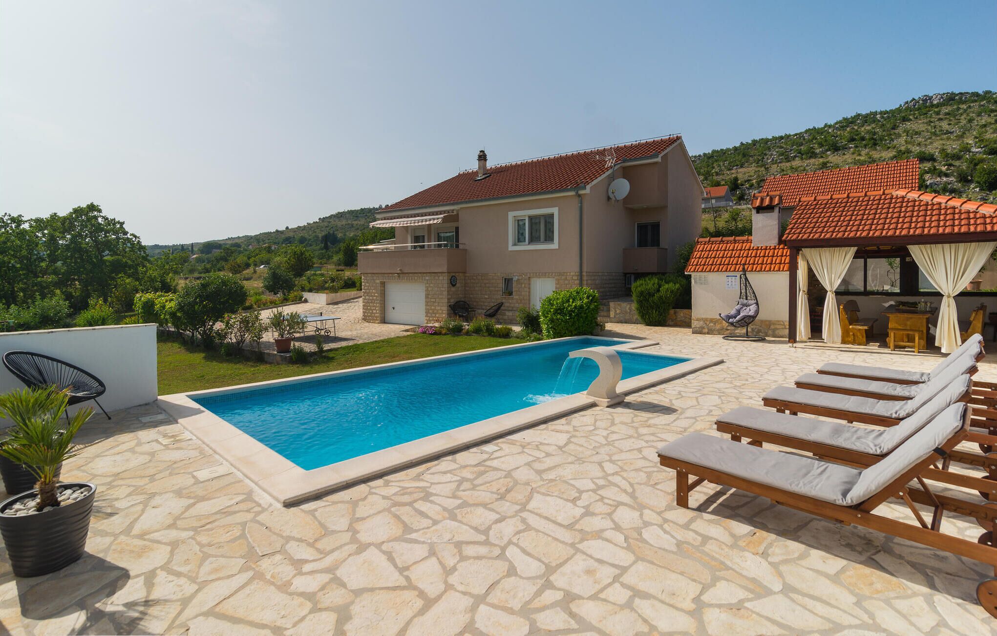 Ein zweistöckiges Haus mit Swimmingpool, Sitzgelegenheiten im Freien und Blick auf die umliegende Landschaft.