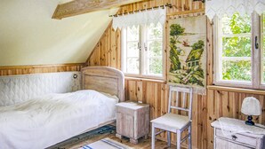 Un dormitorio rústico con una cama de madera, una silla, una mesita y un cuadro en la pared.
