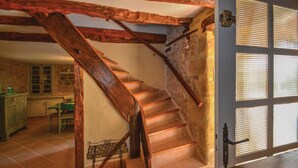 Un escalier en bois, doté d’une rampe en fer forgé, mène à une pièce avec une grande fenêtre.