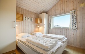 Een slaapkamer met twee bedden, houten wanden, een raam met gordijnen en wandlampen.