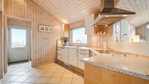 A modern kitchen with wooden walls, a large window, and a tiled floor. - 3 bedroom lovely home in Rømø (Rømø)