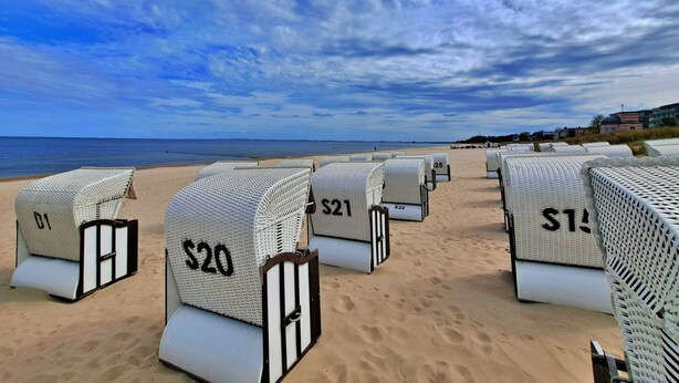 Des chaises de plage avec des étiquettes de prix, sur une plage de sable.