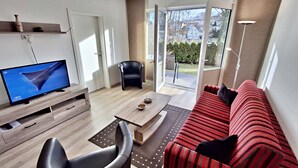 Un salon moderne comprenant un téléviseur à écran plat, un canapé, un fauteuil et un coin repas.