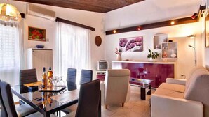 A modern living room with a dining area, featuring a glass table, comfortable seating, and decorative elements like artwork and plants. - Holiday apartment with air conditioning in a quiet location (Valbandon)