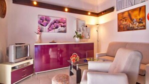 A modern living room with a purple cabinet, a white sofa, and a television on a wooden stand. - Holiday apartment with air conditioning in a quiet location (Valbandon)