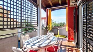 A balcony with a round table and chairs, a view of the neighborhood, and a red wall. - Holiday apartment with air conditioning in a quiet location (Valbandon)