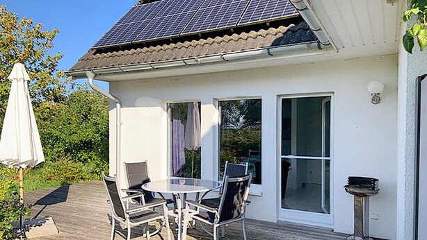 A house with a patio, a table with chairs, and a solar panel on the roof. - Apartment 2 - Cozy in the attic - Apartment Burgert Family (Patzig)