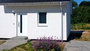 A white building with a dark roof, a small window, and a door. - Apartment 2 - Cozy in the attic - Apartment Burgert Family (Patzig)