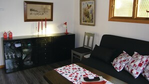 A living room with a wooden cabinet, a painting of birds, a chair, and a sofa with patterned cushions. - 2 bedroom stunning home in Unnaryd (Unnaryd)