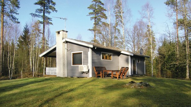 A small cabin with a porch, a chimney, and a window overlooking a grassy yard surrounded by trees. - 2 bedroom stunning home in Unnaryd (Unnaryd)
