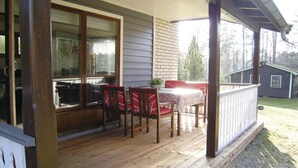 A wooden deck with a table and chairs, a covered area, and a view of a house in the background. - 2 bedroom stunning home in Unnaryd (Unnaryd)