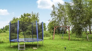 A trampoline with a safety net in a grassy outdoor area.