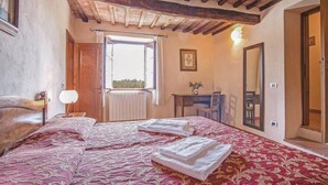 Une chambre à coucher avec un grand lit, un plafond en bois, une fenêtre donnant sur un beau paysage, un bureau et un miroir.