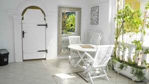 A white door with a black handle, a white-framed mirror, a white table with chairs, and a potted plant with green leaves. - Holiday apartment near the beach with air conditioning (Baška)