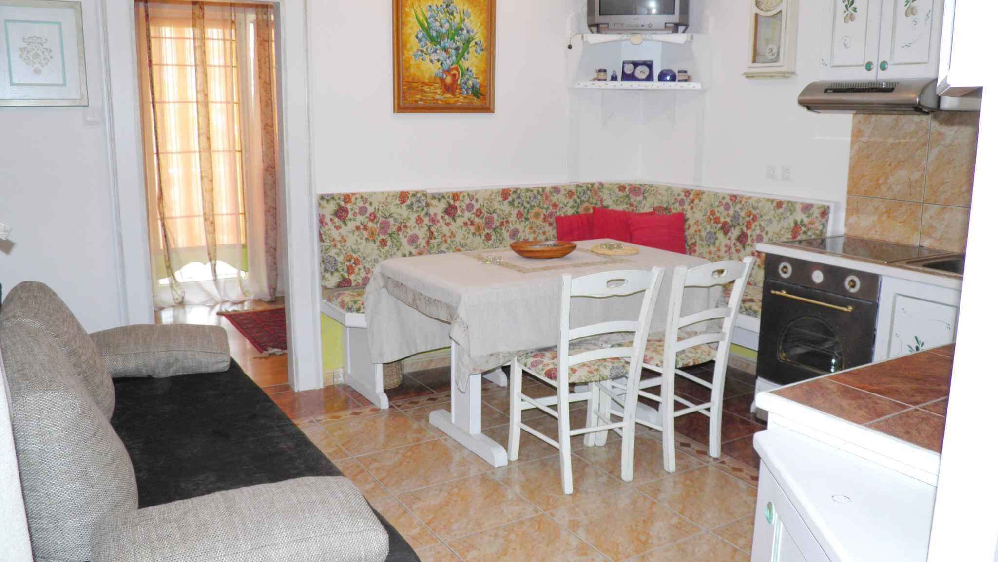 Cocina compacta con mesa, sillas, sofá y lavadora.