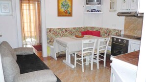 A compact kitchen with a dining table, chairs, a sofa, and a washing machine. - Holiday apartment near the beach with air conditioning (Baška)