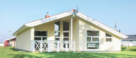 A single-story building with a pitched roof, large windows, and a white porch with a railing.