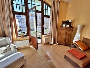 A living room with a sofa, a wooden cabinet, and a view of the outside through large windows.