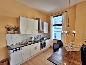 A modern kitchen with white cabinets, a black countertop, and a wooden dining table.