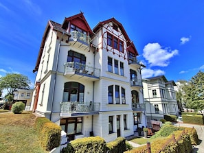 A multi-story building with balconies, large windows, and a well-maintained garden.