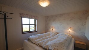 Ein Schlafzimmer mit einem Bett, einem Fenster und zwei Wandlampen.