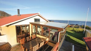 Ein Haus mit einer verglasten Terrasse, einem roten Dach und Blick aufs Meer.