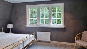 Ein Schlafzimmer mit Bett, Heizkörper, Fenster und Stuhl.