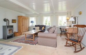 Relax in this inviting living room with a sofa, armchair, and rocking chair, plus a dining table and stove.