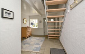 Stairwell leading to an upper floor with a wooden ladder and a small dresser.
