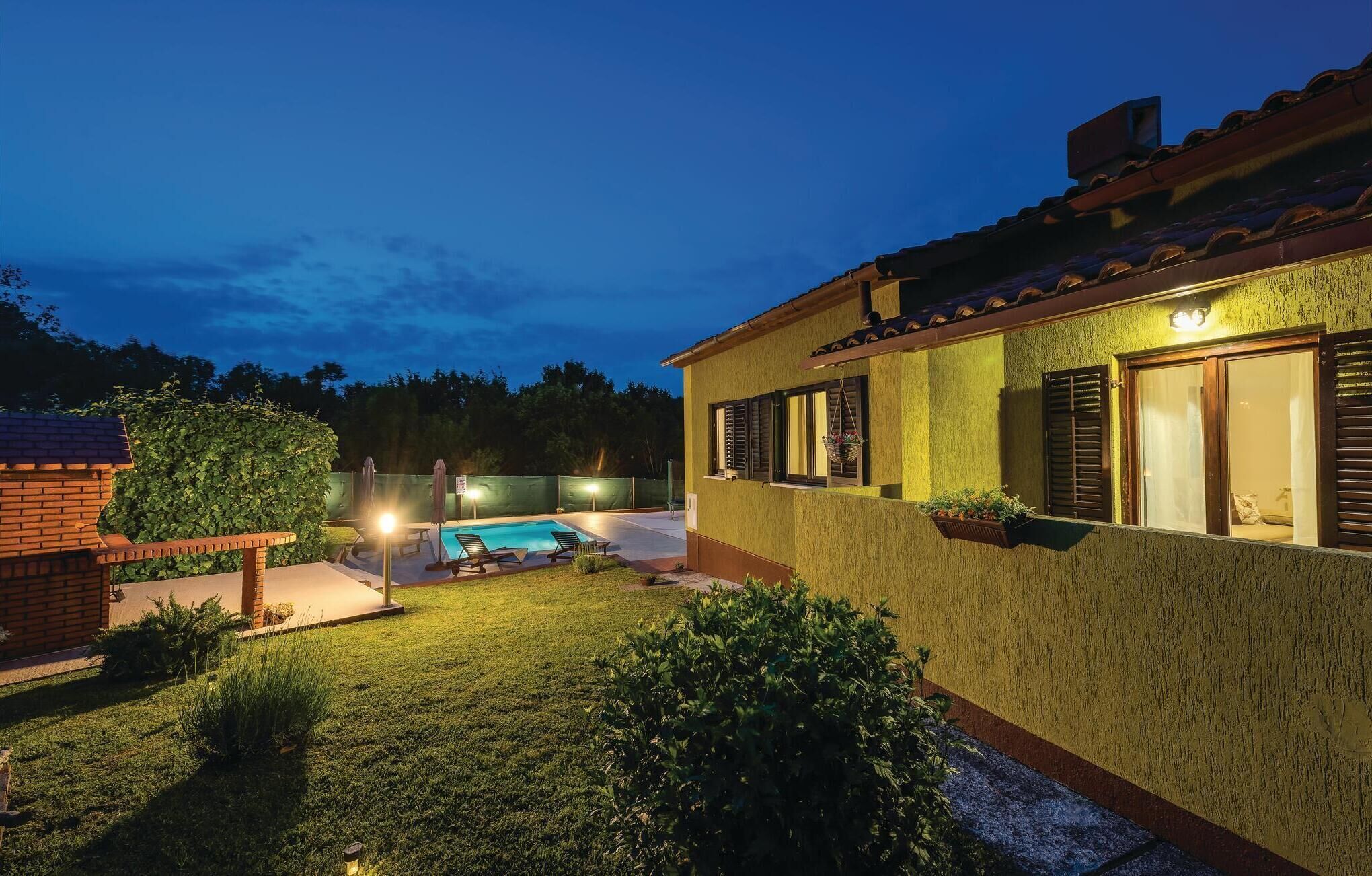 A house with a swimming pool, a brick structure to the left, and a well-maintained lawn.